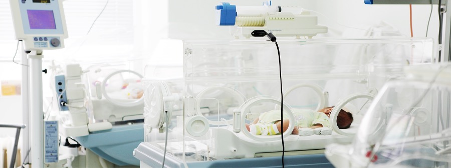1 of 1, Preterm infant in a hospital incubator with a feeding syringe on the top