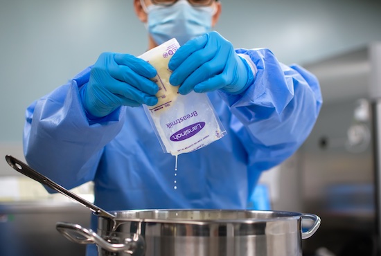 Milk technician emptying a bag of human milk into a container